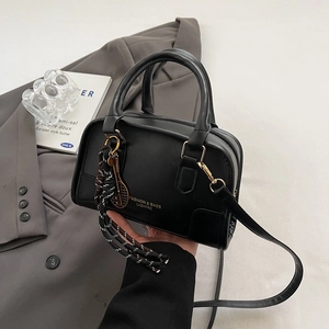 Minimalist black leather crossbody bag with tennis racket charm on grey blazer