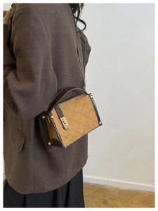 Detail of a brown quilted box bag with gold twist lock and adjustable shoulder strap