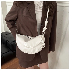Détail du sac demi-lune blanc avec bandoulière nouée et perles décoratives chic