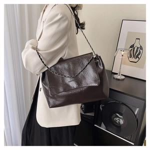 Détail du sac à bandoulière en cuir froissé marron foncé avec bandoulière chaîne argentée en intérieur