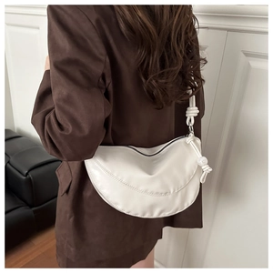 Detailed close-up of white crescent crossbody bag with unique shoulder strap knot design