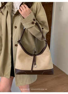 Detailed close-up of a two-tone minimalist retro hobo bag with suede texture and metal ring