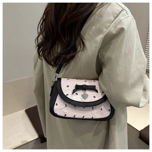 Gros plan du sac rose à motifs nœuds noirs avec pendentif cœur argenté en détail
