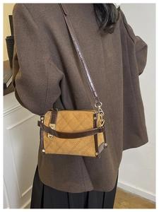 Detail view of mustard yellow quilted crossbody bag with brown trim and gold hardware accents