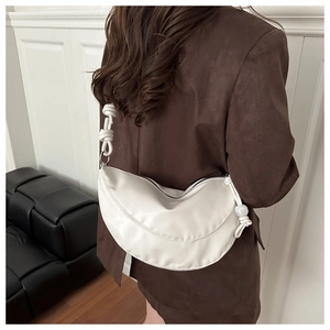 Détail du sac hobo blanc avec bandoulière nouée et accent de perle décorative sur l'épaule