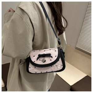 Détail du sac bandoulière rose avec nœuds noirs et pendentif cœur argenté porté