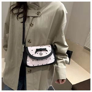 Détail du sac à bandoulière rose à nœud avec pendentif cœur porté sur un mannequin