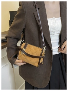 Close-up of retro mustard yellow crossbody bag with brown trim and quilted stitching