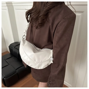 Detail of white PU leather crescent bag featuring a chunky knot strap and pearl accent