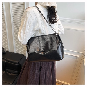 Détail du sac bandoulière en cuir plissé noir brillant avec bandoulière chaîne vintage