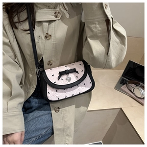 Détail du sac bandoulière rose avec nœuds noirs et pendentif en cœur argenté