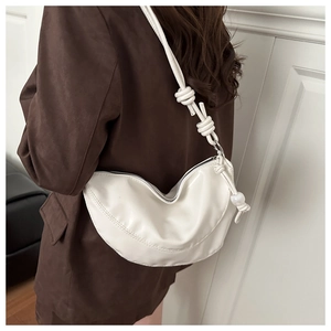 Détail du sac demi-lune blanc avec bandoulière en corde nouée et pendentif perlé sur manteau