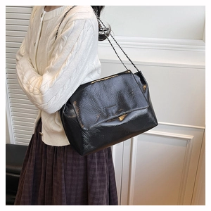 Side view of black glossy patent leather shoulder bag with fine silver chain strap