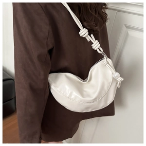 Détail d'un sac demi-lune en cuir blanc avec breloque perle et bandoulière nouée