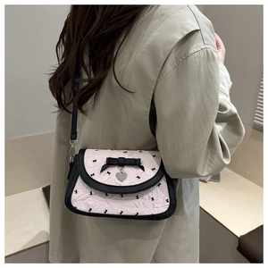 Détail du sac plissé rose avec nœuds noirs et pendentif cœur porté par le mannequin