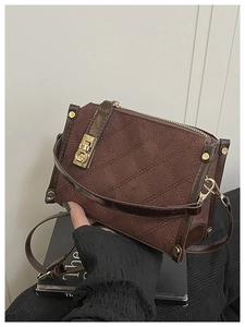 Detail of brown quilted faux suede crossbody bag featuring gold hardware lock and stitching