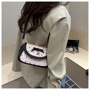 Détail du sac à bandoulière rose avec lapins noirs, nœud et pendentif en cœur