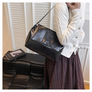 Close-up of black wrinkled faux leather shoulder bag with chic silver chain strap
