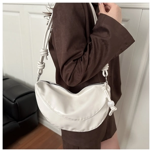 Détail du sac demi-lune blanc avec bandoulière à nœud décoratif et ornement en perle