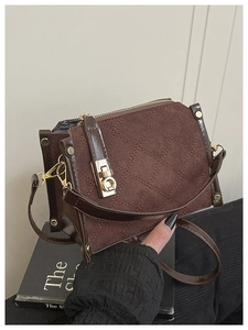 Close-up of brown quilted corduroy bag with golden turn-lock and leather shoulder strap
