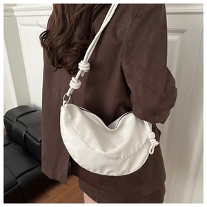 Détail du sac lune blanc avec bandoulière nouée et tirette en perle sur cuir texturé