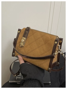 Detail of vintage brown quilted crossbody bag with metal turn-lock and gold studs