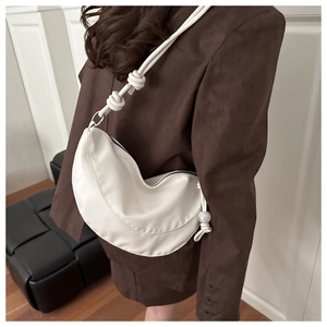 Sac demi-lune blanc avec bandoulière nouée et perle sur un blazer marron