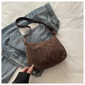 Detail of leopard print crossbody bag with adjustable strap on denim jacket and white sheets