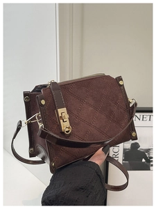 Detail of dark brown quilted suede box bag with gold twist lock and elegant leather piping
