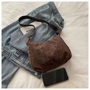 Detailed view of leopard print crossbody bag styled over a casual denim jacket