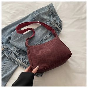 Detailed view of burgundy leopard print hobo bag on textured fabric background