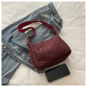 Detail view of burgundy leopard print nylon crescent bag with adjustable shoulder strap