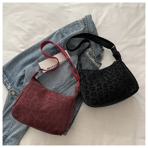 Flat lay of leopard print shoulder bags in wine red and black with wide straps