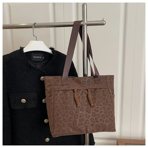 Détail du sac cabas léopard avec des glands tressés et une poche latérale pratique