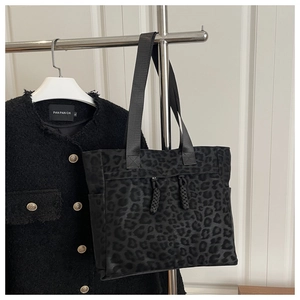 Détail d'un grand sac cabas imprimé léopard avec bandoulière tressée et pompon zippé