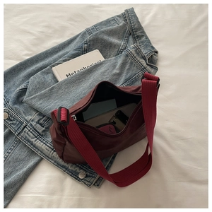 Top view of a burgundy crossbody bag with wide strap, showing interior space and phone
