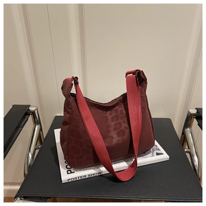 Detail of dark red leopard print crescent bag with textured jacquard and woven strap