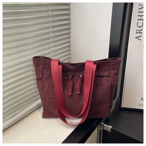 Détail du sac cabas en toile bordeaux imprimé léopard avec poignées en sangle rouge