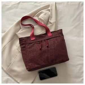 Détail du sac cabas bordeaux à motif léopard avec bandoulières roses et poche latérale