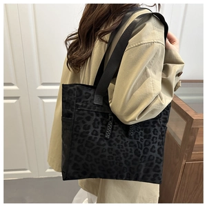 Détail du sac cabas léopard noir avec corde tressée porté sur un manteau beige chic