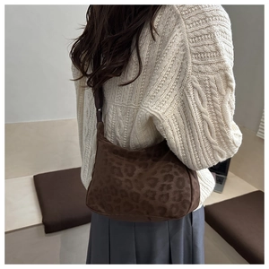 Close-up of brown leopard print crescent bag with soft suede texture and adjustable strap