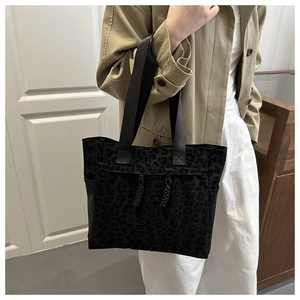 Détail de l'imprimé léopard noir et des poignées tissées durables sur le sac fourre-tout