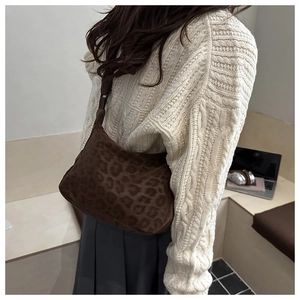 Detailed back view of a vintage leopard print hobo bag worn by a model in a modern office