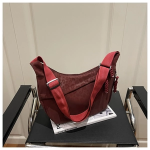 Détail du sac en nylon bordeaux imprimé léopard avec bandoulière rouge sur chaise noire