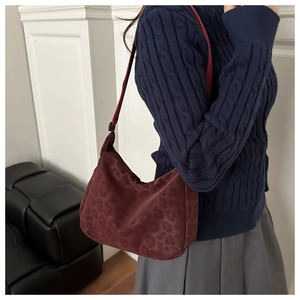 Detail of burgundy leopard print tote bag with wide strap on a navy knit sweater