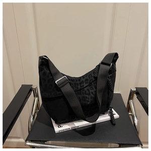 Détail d'un sac demi-lune jacquard léopard noir posé sur un livre d'art blanc