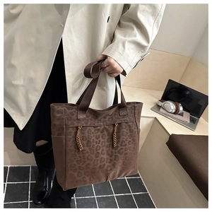 Détail du sac cabas léopard avec pompons marron et texture de toile résistante