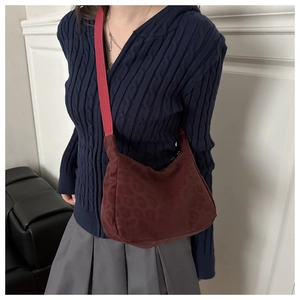 Detail of dark red leopard print shoulder bag with woven strap on a model's arm
