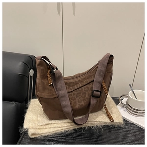 Gros plan du sac hobo léopard avec large bandoulière sur tissu en peluche beige
