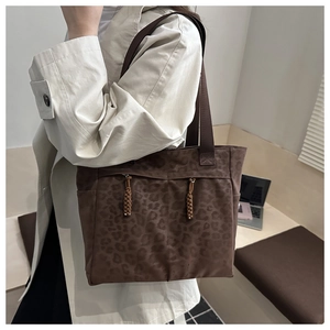 Close-up of brown leopard print tote bag featuring woven tassel detail and large capacity